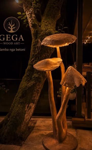 Llamba dekorative në formë kërpudhe, të gdhendura nga druri masiv, të ndriçuara natën para punishtes Gega Wood Art